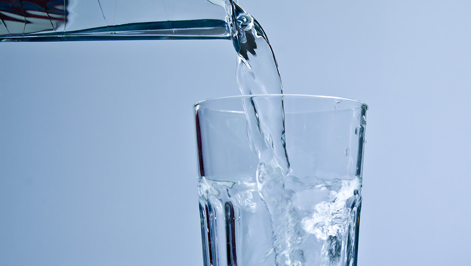 Fotografi av ett dricksglass som fylls med vatten från en kran.