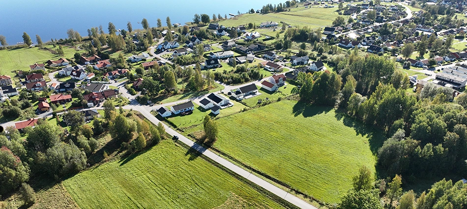 Flygbild över området Stenäs. På bild syns ett grönområde, flera hus och Norasjön.